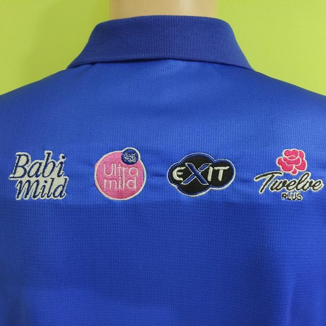 โลโก้แบรนด์ในเครือ Babi Mild Ultra Mild EXIT Twelve Plus ปักที่หลังเสื้อ